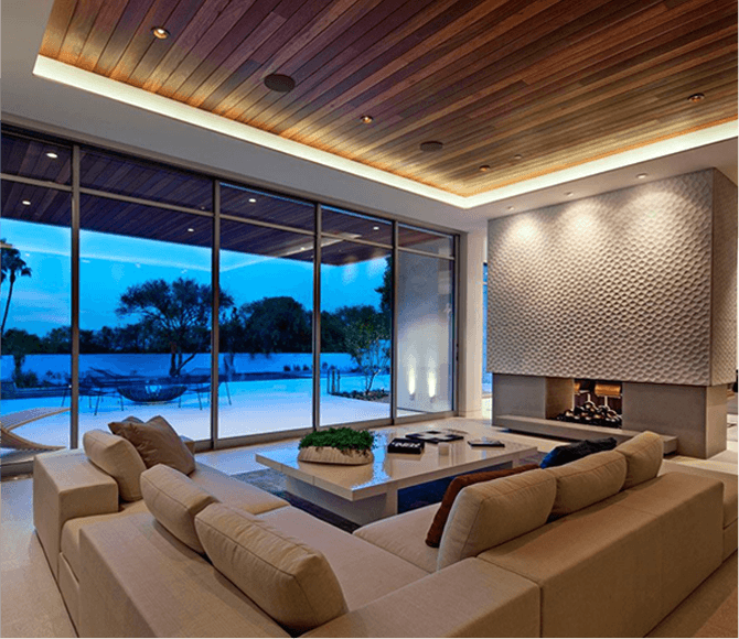 Modern living room with large windows overlooking a pool and outdoor area at dusk.