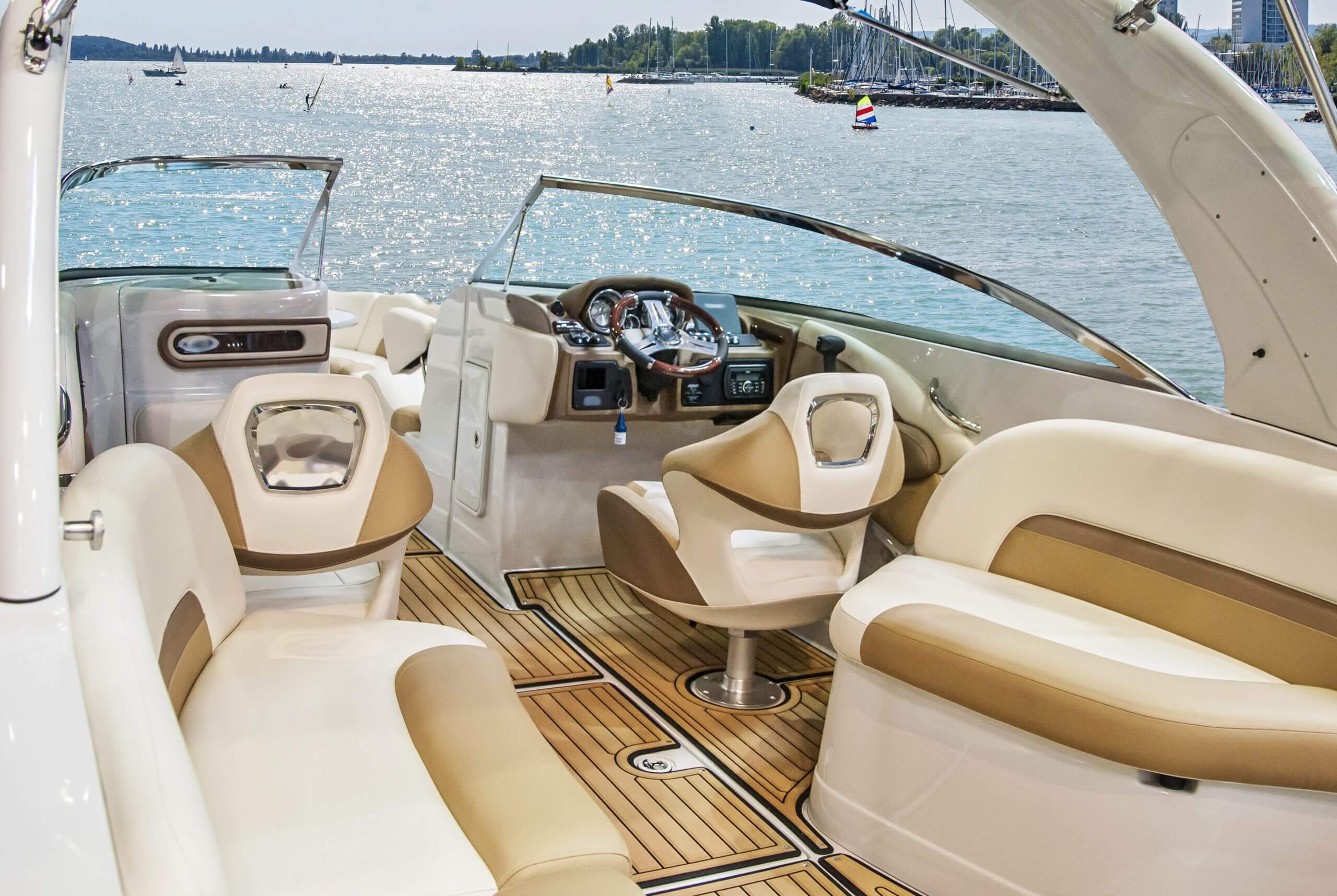 Luxurious boat interior with beige seating and wooden flooring under bright sunlight.
