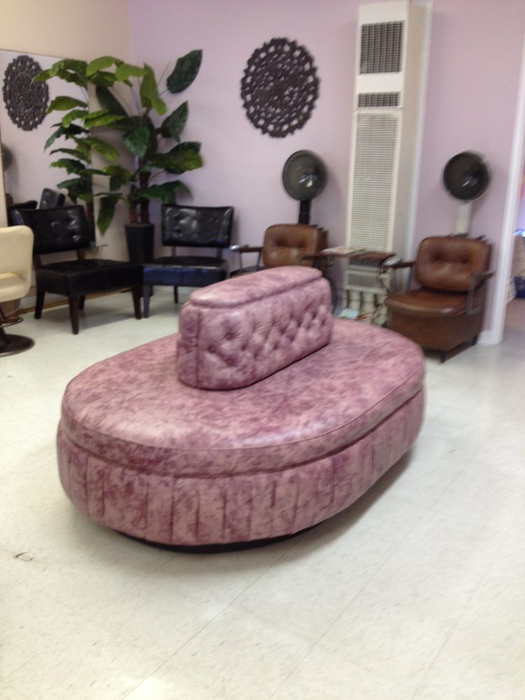 A plush, pink velvet ottoman with a backrest in a stylish room.