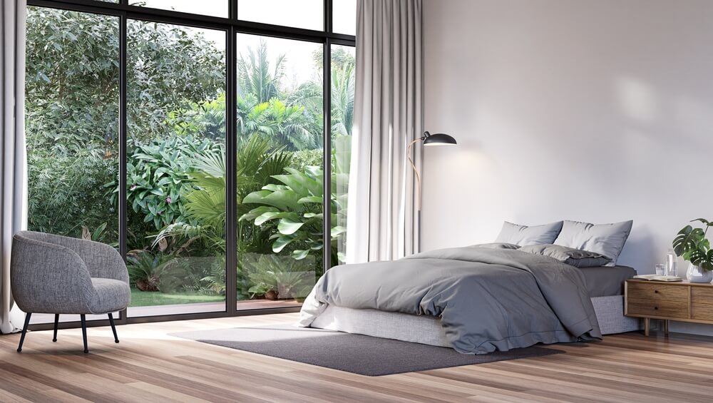 Cozy bedroom with large window overlooking lush greenery.