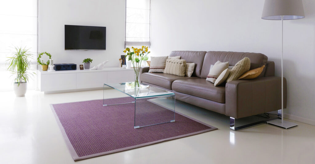 Modern living room with a glass coffee table and a purple rug.