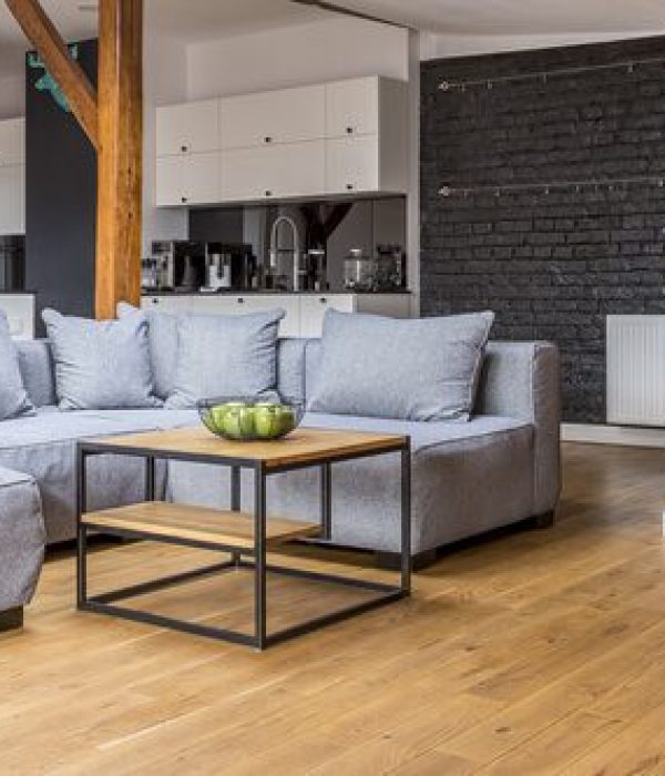 Modern living room with gray sectional sofa and wooden coffee table.