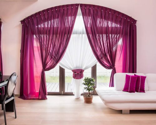 Elegant living room with purple curtains and cozy white sofa.